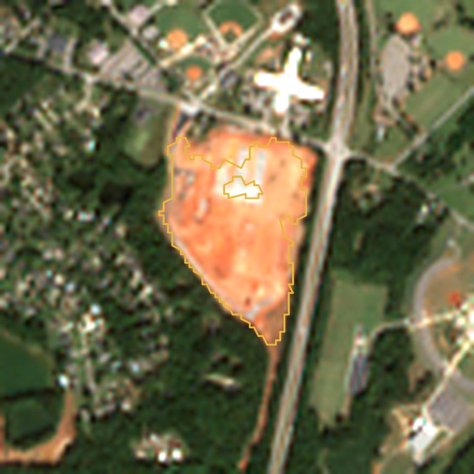 Satellite view in October 2026: 24 acres of bare red clay with a pad, outlined in gold